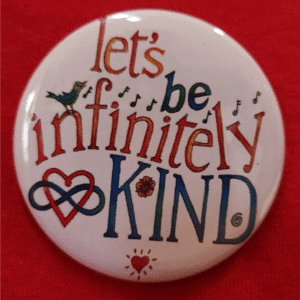 Let's be infinitely Kind button on red shirt